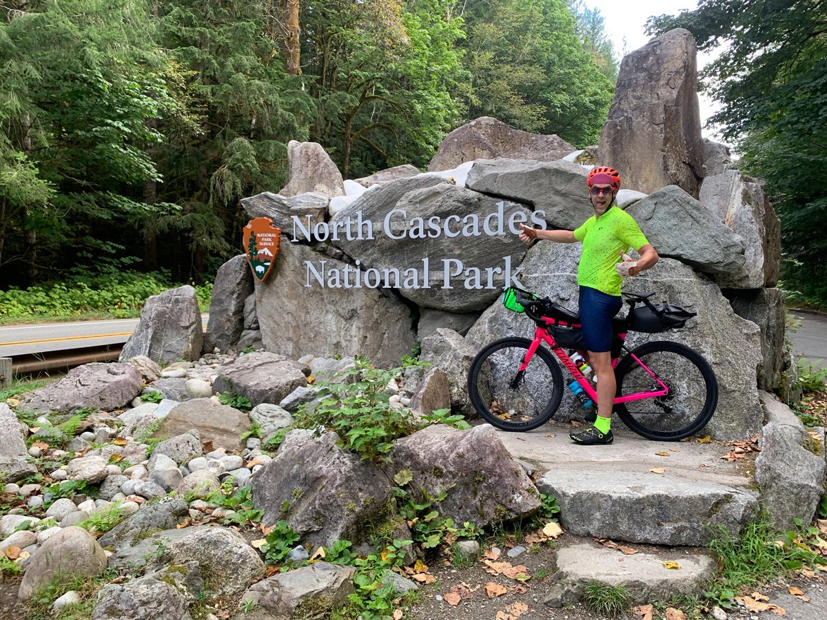 Rob Lea posing with bike in front of sign for North Cascades National Park.